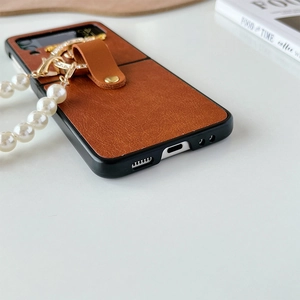 Dettaglio custodia Z Flip in pelle marrone con catena di perle e ciondolo strass