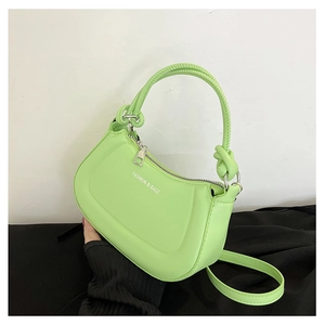 Detail of neon green crossbody bag featuring a knotted handle and fashion text print