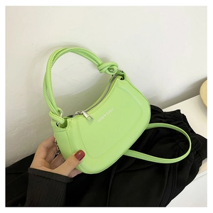 Close-up of light green crescent handbag with knotted handle and fashion text detail