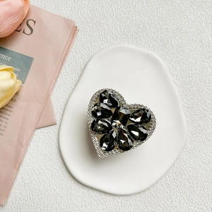 Detail view of heart-shaped rhinestone phone socket with black gems on white ceramic tray