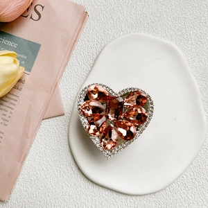 Close-up of heart-shaped rhinestone phone socket with amber crystals on ceramic plate