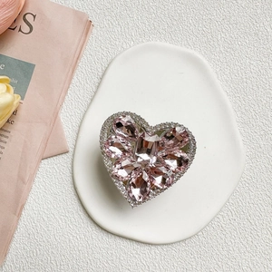 Macro shot of luxurious heart-shaped phone grip with pink crystals and micro-inlaid diamonds