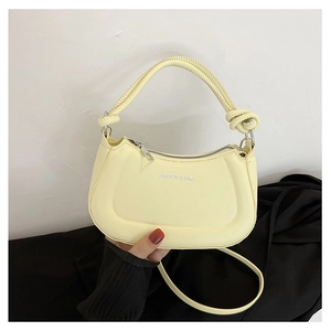 Detail of light yellow crescent bag featuring a knotted handle and fashion text print