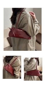 Detail of dark red glossy shoulder bag featuring decorative side bows and white lettering