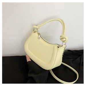 Detail of light yellow crescent bag with knotted handle and silver metal ring hardware