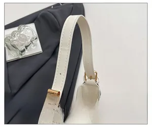 Close-up of cream white shoulder bag strap with gold metal buckle and crossgrain texture