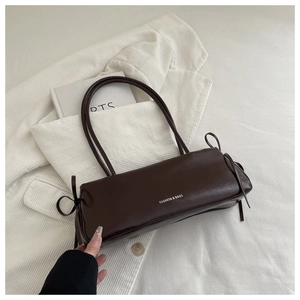 Detail of dark brown faux leather shoulder bag with side bow drawstring and dual straps