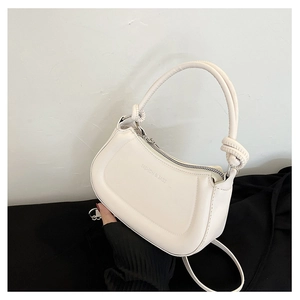 Detailed view of white half-moon handbag with knotted handle and fashion lettering