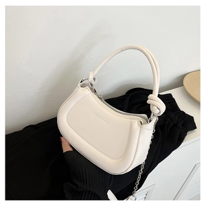 Detail of off-white crescent bag with knotted handle and silver chain strap