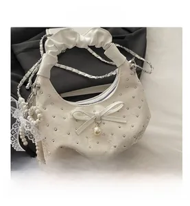 Detail of white pleated handbag with silver studs, bow decor, and pearl lace charm