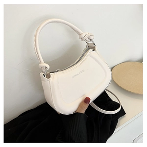Detail of white half-moon leather bag with knotted handle and logo printing