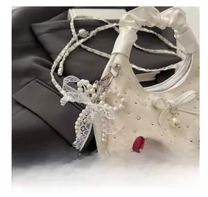 Detail of white crescent bag with pleated handle, lace pearl bow, and sequined texture