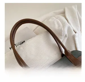 Detail of retro suede tote bag featuring brown leather handle and gold metal buckle
