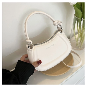 Detail of cream white PU leather crossbody bag with FASHION & BAGS print on wooden tray