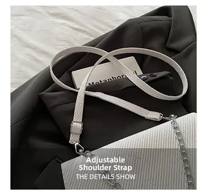 Détail de la bandoulière réglable et de la chaîne argentée sur le sac blanc texturé