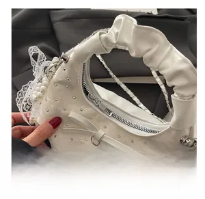 Detailed close-up of white pleated crossbody bag with bow, pearls and silver zipper