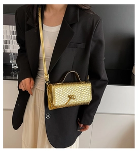 Detail of a gold textured mini bag featuring a knot clasp and metallic top handle