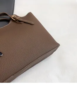 Detail of dark brown pebble leather tote bag featuring stitching and gold buckle