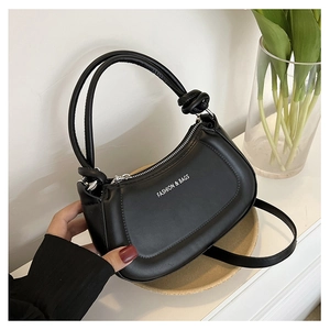 Close-up of black crescent moon bag with knotted handle and white fashion text logo