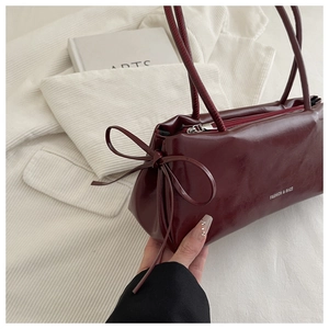 Close-up of wine red leather bag showing the side bow detail and metallic zipper texture
