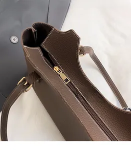 Close-up of coffee brown lychee leather bag with white stitching and gold zipper detail