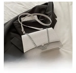 Gros plan détaillé du sac bandoulière blanc texturé posé sur une veste de costume noire