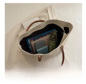 Detail showing the large capacity interior of this tote bag with tablets and umbrella