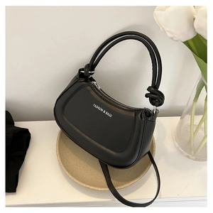 Detailed macro view of black hobo bag featuring knotted handle and subtle matte leather texture