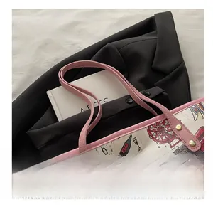 Close-up of pink leather handles and urban print details on the beige tote bag