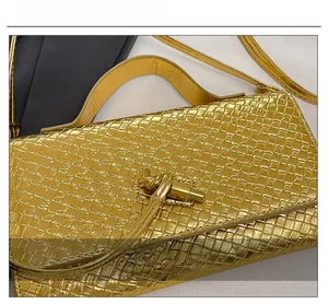 Detail of gold woven texture and metallic knot buckle on the fashion baguette bag
