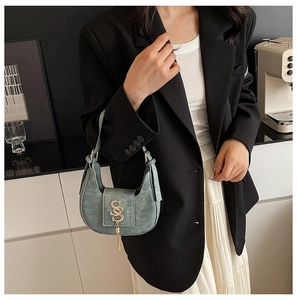 Detail of a crescent shoulder bag in matte bluish-grey leather with a gold S-shaped logo