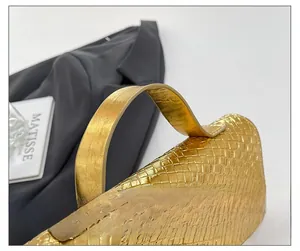 Detail of golden woven texture handbag with comfortable wide top handle and metallic finish