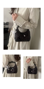 Detail of elegant black pleated handbag with pearl charms, lace accents and silver chain