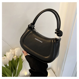 Detail of black leather hobo bag with knotted handle and white fashion typography