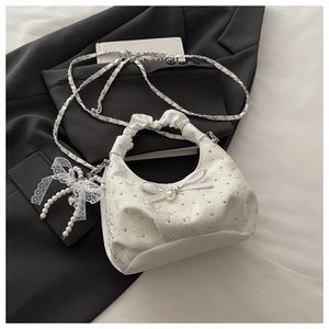 Close-up of white cloud bag featuring sparkling rhinestones, pearl bow and lace detail