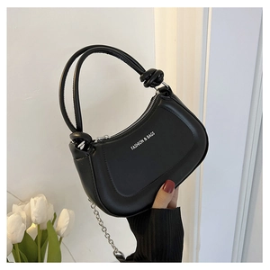 Close-up of black crescent hobo bag with knot detail and silver chain strap