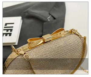 Macro shot of elegant champagne glitter evening bag with golden bow clasp detail