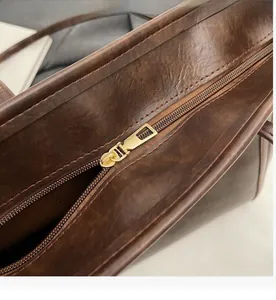 Detail of smooth gold zipper hardware on vintage brown leather tote bag
