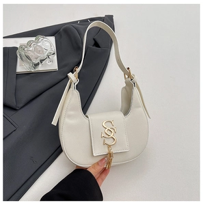 Close-up of beige crescent hobo bag with gold metal logo and stylish tassel detail