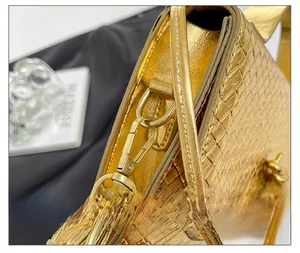 Close-up of high-quality gold metallic lobster clasp and crocodile texture on the handbag