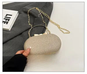Detailed view of mini gold sequin evening bag with metal handle beside a phone for scale