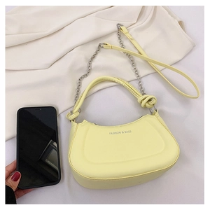 Detail view of small yellow leather crossbody bag next to phone for size reference