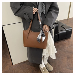 Brown lychee leather tote bag with silk scarf detail worn by model in a grey coat