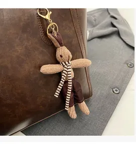 Close-up of a handmade knitted rabbit charm with a striped scarf on a brown tote bag