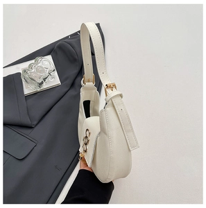 Detail of off-white lychee leather crescent bag with gold ring buckle and adjustable strap