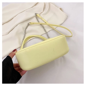 Detail view of the yellow leather handbag showing the curved base and silver chain strap