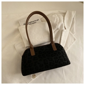 Detail of black leopard print suede tote bag with brown straps on white corduroy fabric