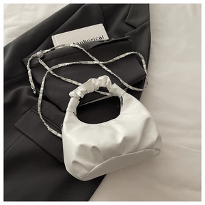 Close-up of white ruched hobo bag with gold metal and leather woven chain strap detail