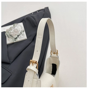 Detail of adjustable golden metal buckle on beige crossbody bag with cross pattern texture
