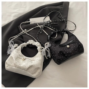 Detailed view of pearl-embellished lace bow handbags in cream and black with chain straps